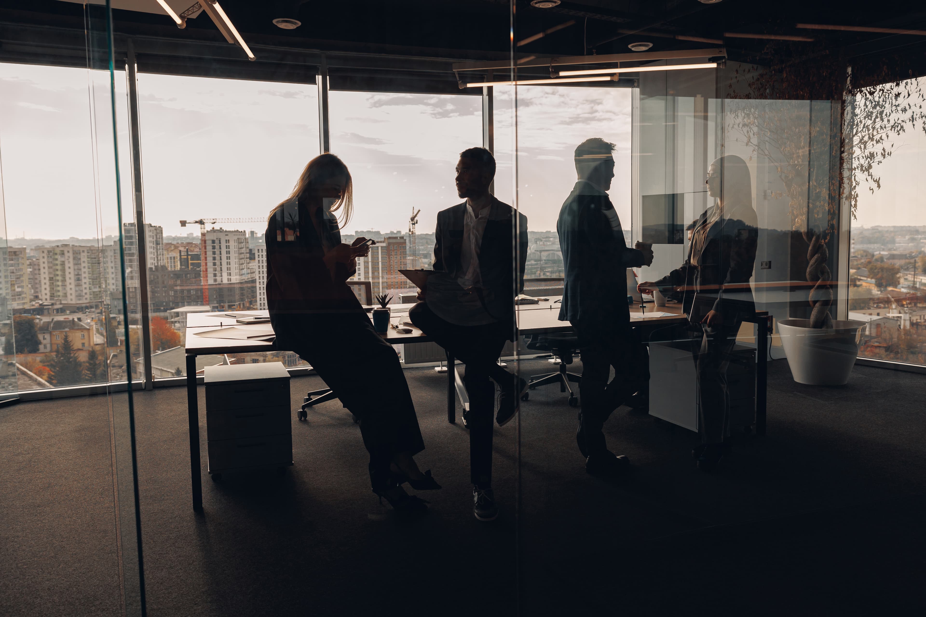 Silhouettes of professionals in a modern office with city skyline